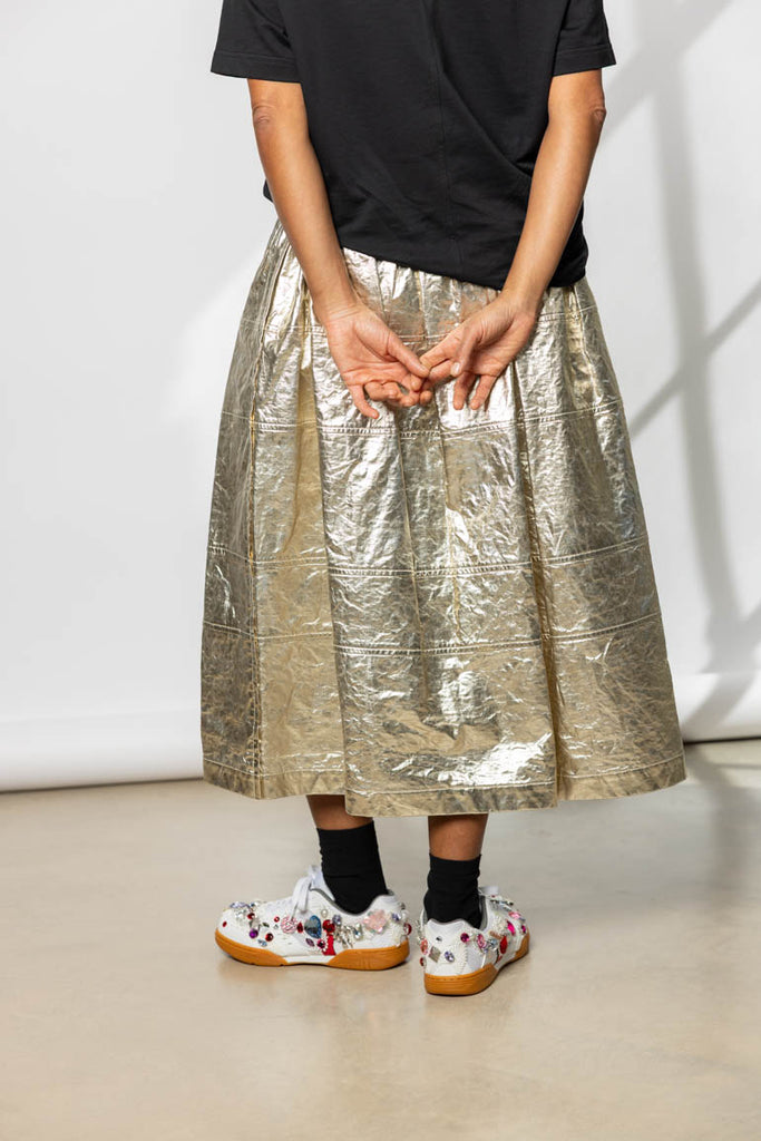 Person wearing a metallic gold skirt with a plain background